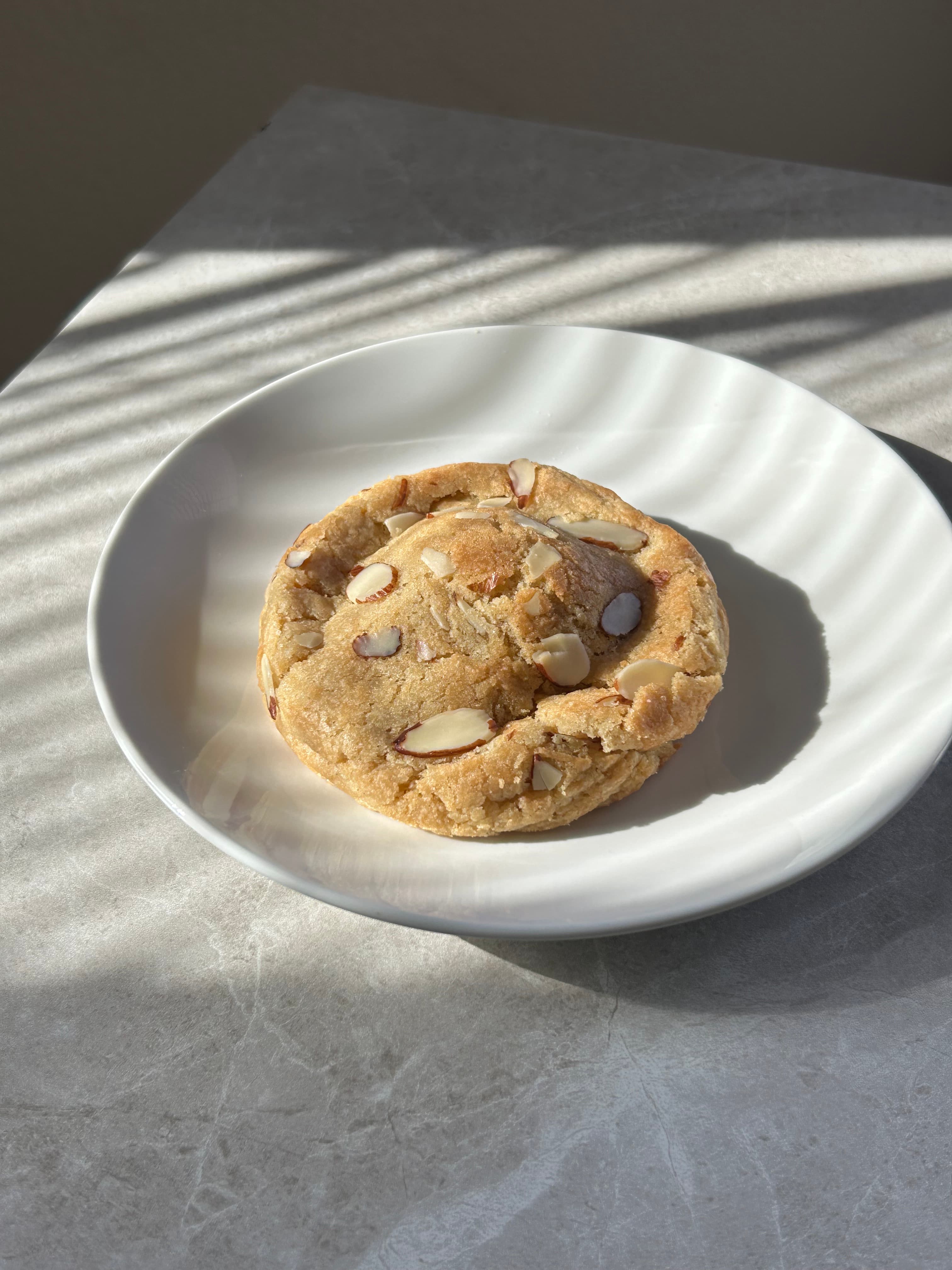 Almond Croissant Cookie Stuffed With Frangipane, Rolled In Almond Slices & Dusted With Powdered Sugar.